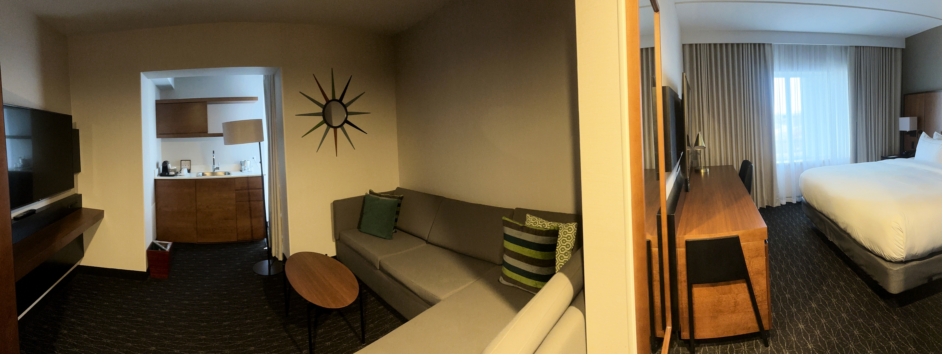 Panorama-Foto, links der Teil der Suite mit Sofa, TV und Küche, rechts das Schlafzimmer mit dem Bett