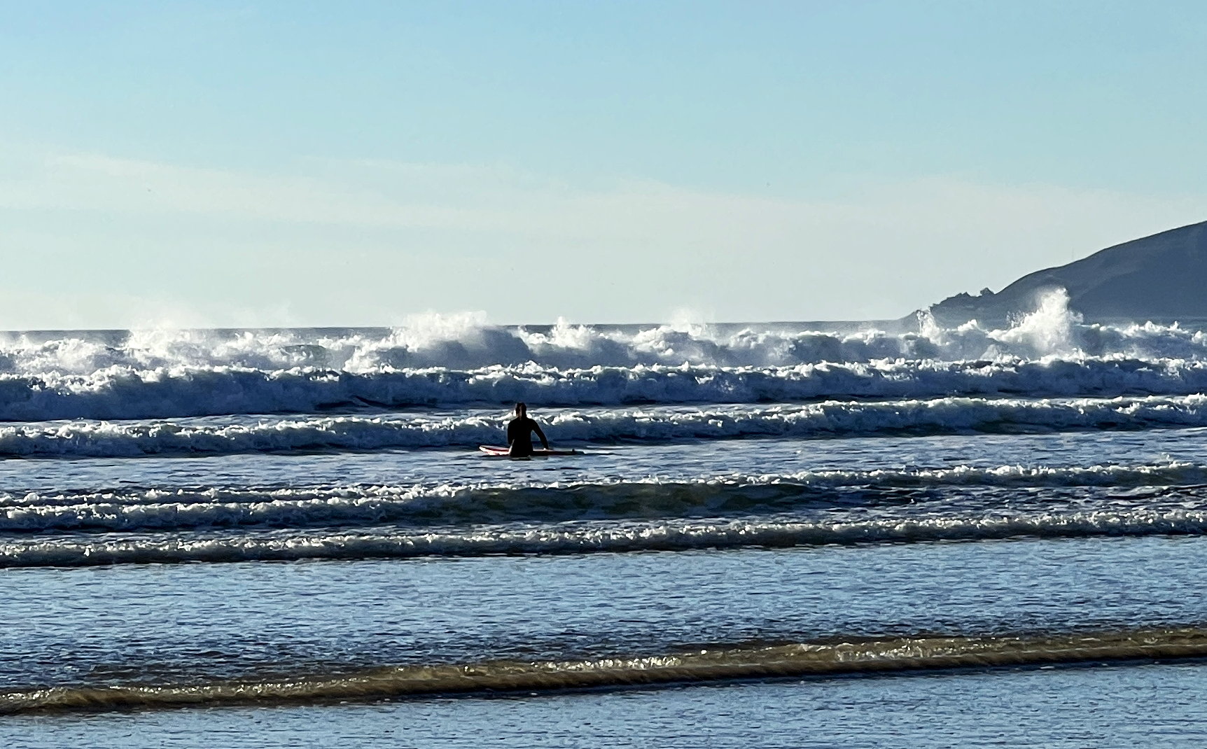 Eine Surferin geht mit ihrem Brett den Wellen entgegen