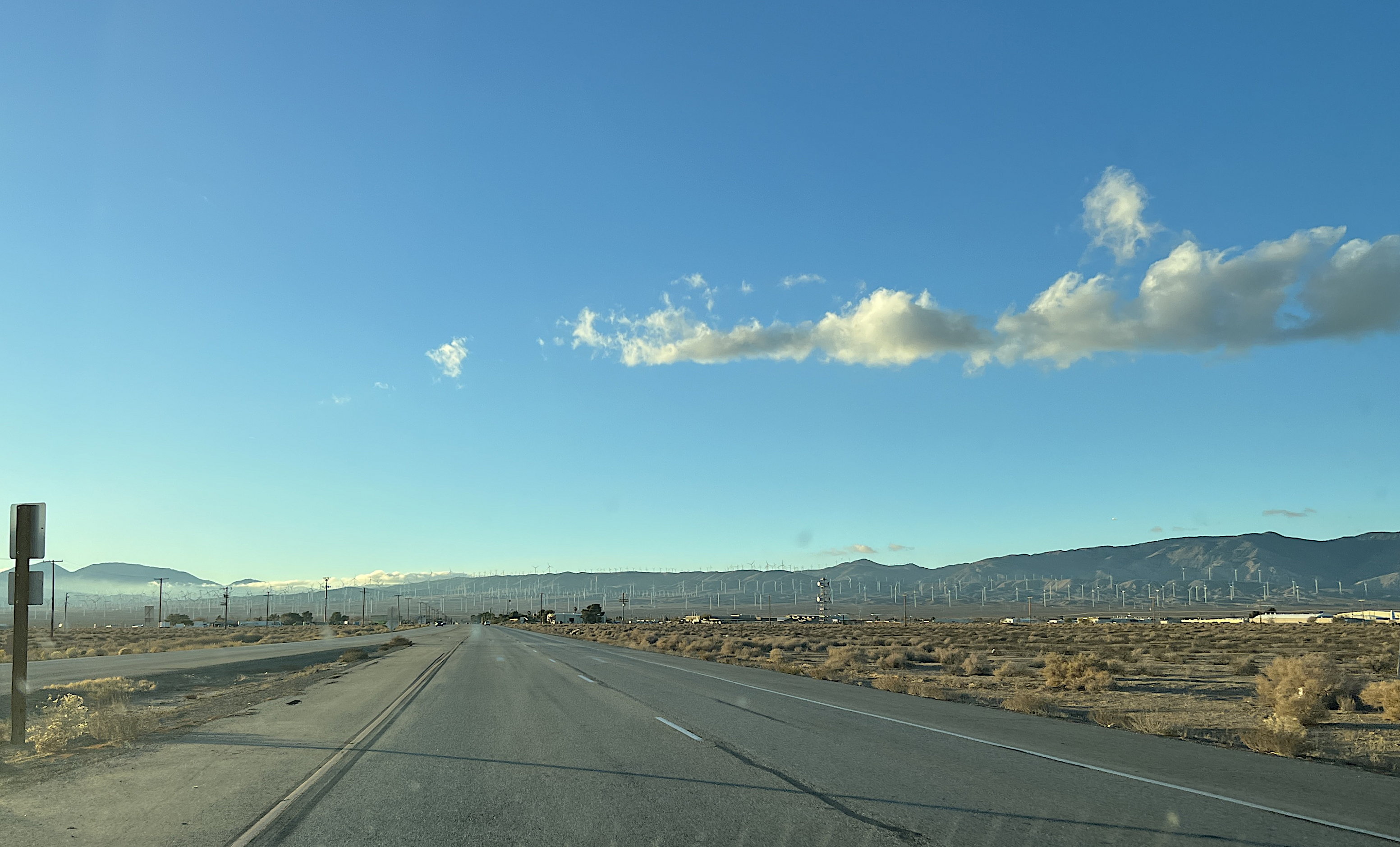Auf dem Highway 58 sieht man in der Ferne an den Hängen viele Windräder, darüber der blaue Himmel.