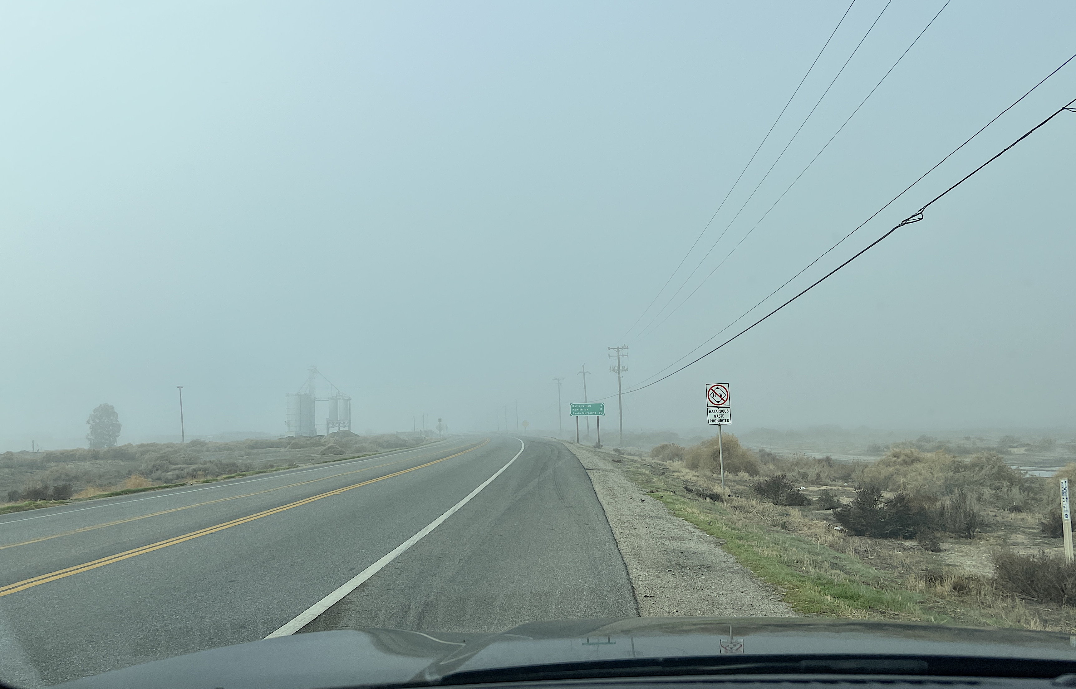 Der Highway bei Buttonwillow. Die Strasse führt direkt in den Nebel. Man erahnt ein Silo am Strassenrand.