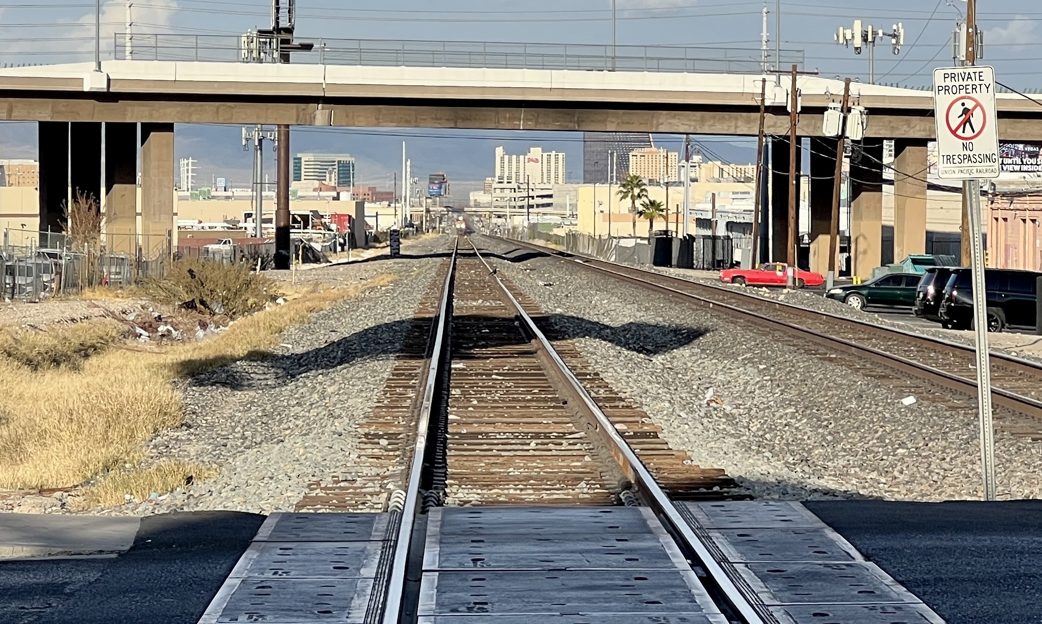 Ich stehe auf dem Bahnübergang einer zweispurigen Eisenbahn. Auf der linken Spur sieht man undeutlich die Konturen eines herannahenden Zugs.