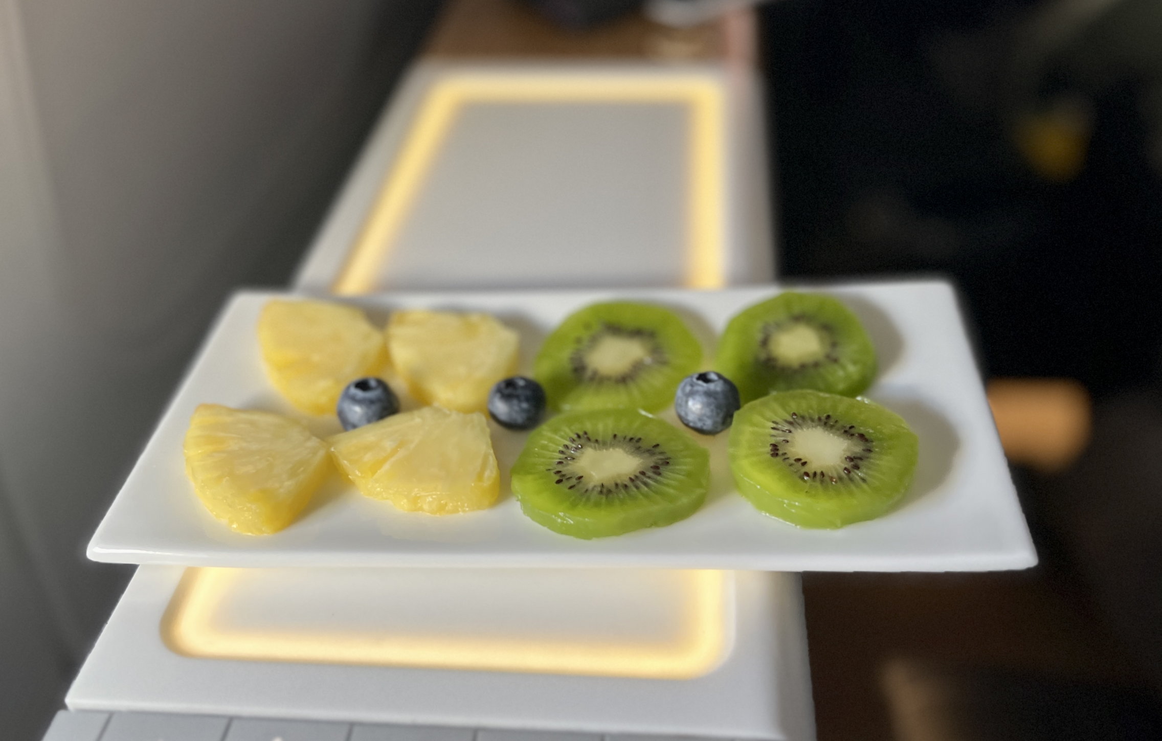 Dessertteller mit Ananas-Stückchen und Kiwi-Scheibchen, garniert mit drei Blueberries