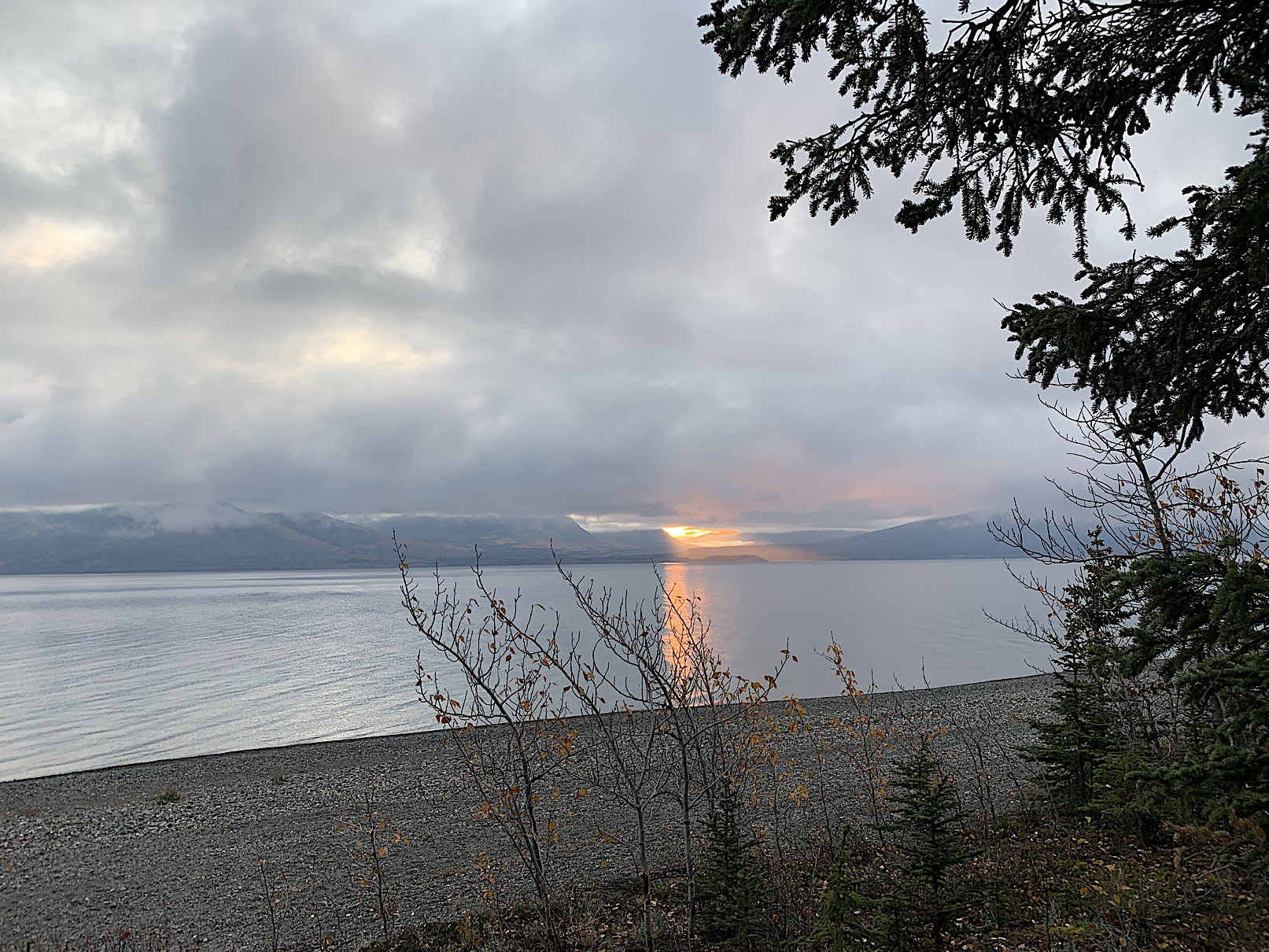 Morgenstimmung über dem Kluane Lake, die Sonne scheint durch eine Lücke und er Nebel-/Wolkendecke