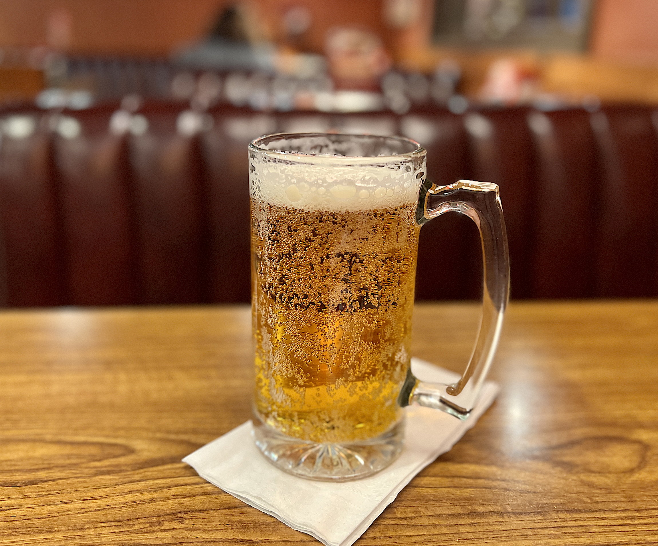 Ein grosser Humpen mit perlendem Bier und einer kleinen, eher dünnen Krone.