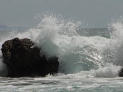 Wellen brechen über die Felsen am Hotwater Beach