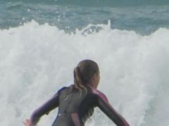 Surferin gleitet aus den Wellen am Strand von Tauranga