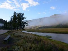Erste Sonnenstrahlen beleuchten die Berggipfel, im Tal liegt noch der Morgennebel beim Madison River im Yellowstone Nationalpark