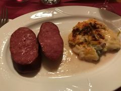 Eine Portion Treberwurst mit Kartoffelgratin und Lauch